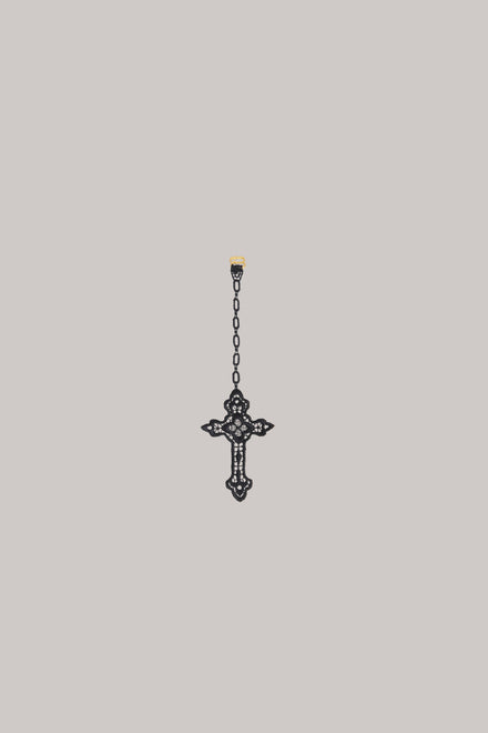 A crocheted cross on  grey background.