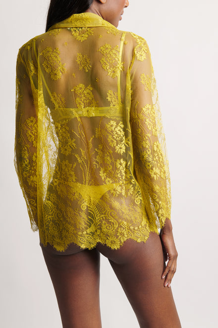 Yellow lace sheer blouse worn by a model on a white background