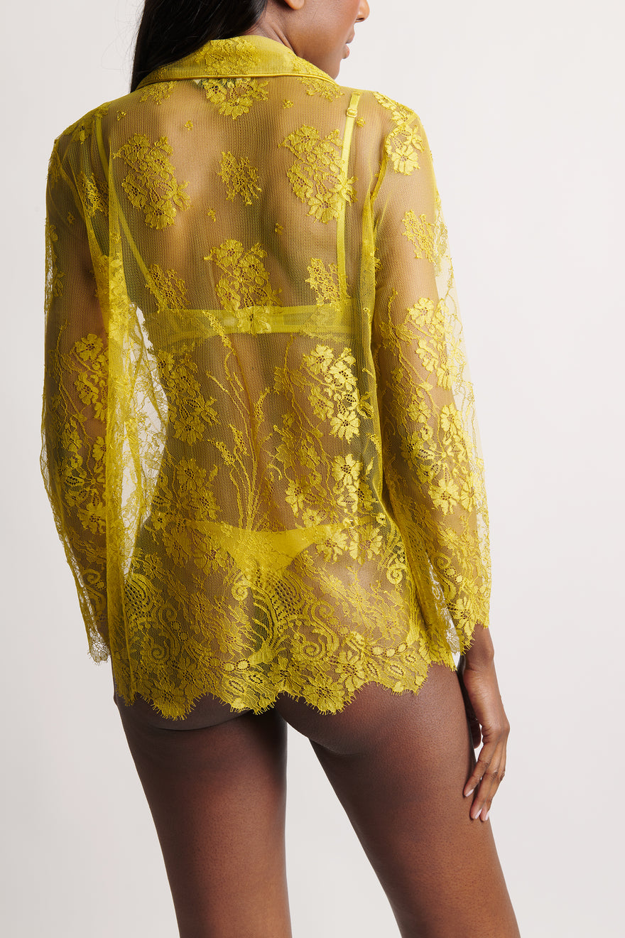 Yellow lace sheer blouse worn by a model on a white background
