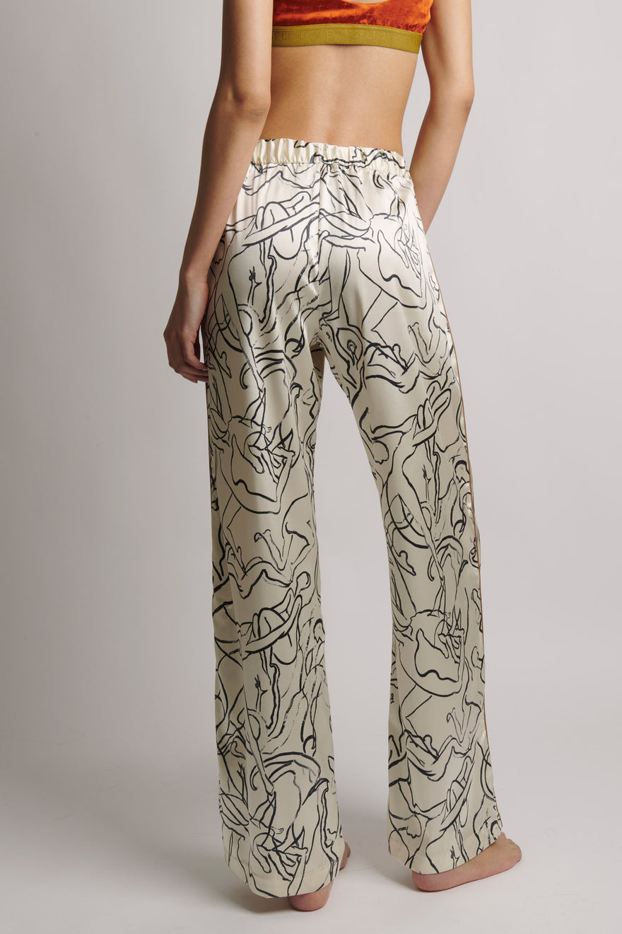Person wearing a pair of wide-leg pants with abstract black line art on a plain background