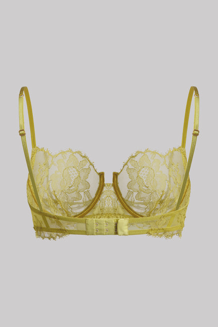 A pale yellow lace underwire bra with matching thin shoulder straps and a decorative center band, shown against a solid gray background.