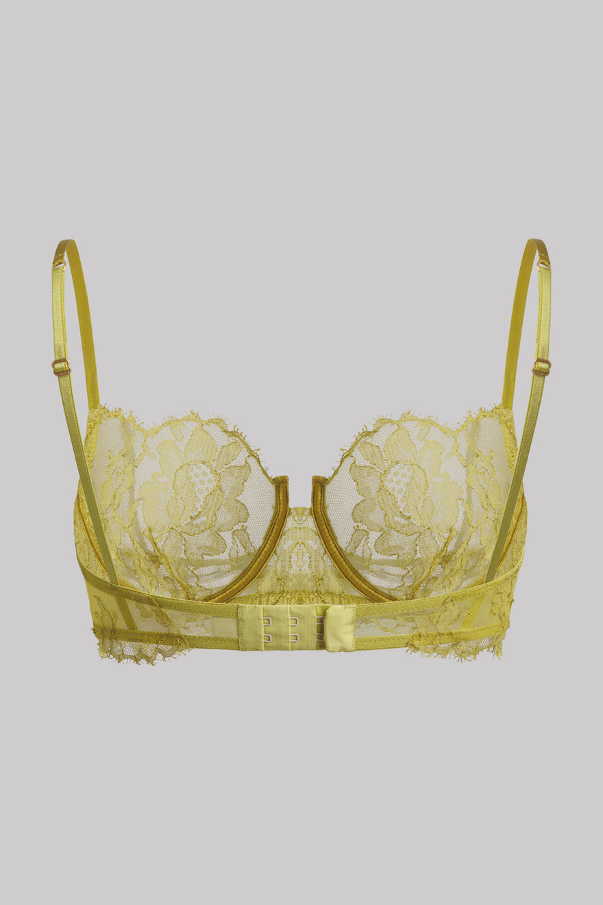 A pale yellow lace underwire bra with matching thin shoulder straps and a decorative center band, shown against a solid gray background.