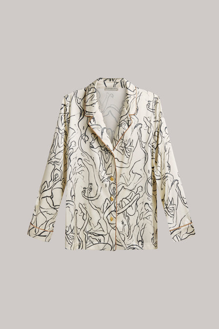 A long-sleeve button-front shirt jacket with a soft, flowing silhouette and an abstract black line art print on a warm cream background, shown against a solid light gray background.