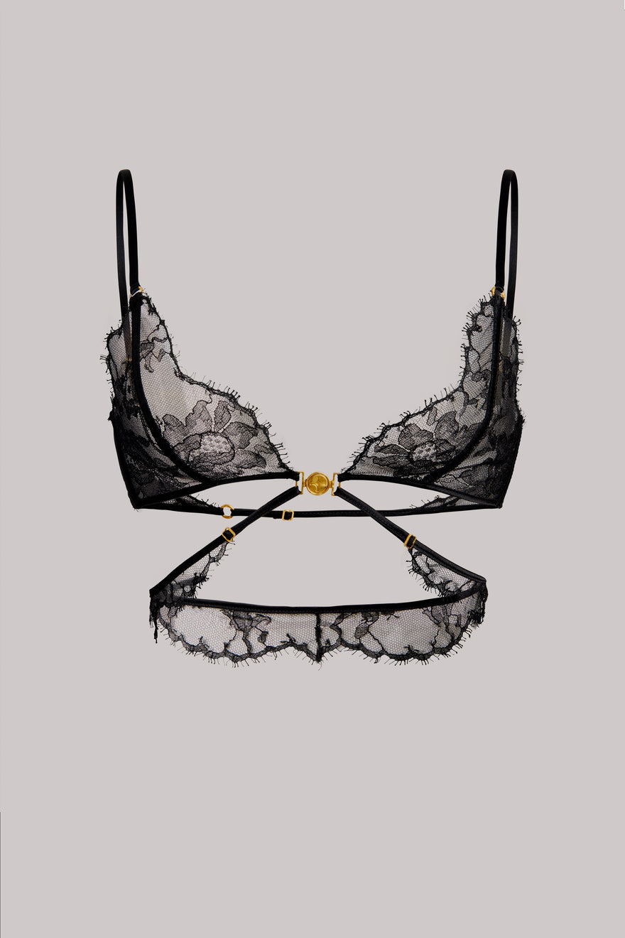 Black lace lingerie set featuring a bra with floral lace cups and thin straps, paired with a matching garter belt and waistband, accented by a central gold-tone clasp, shown against a solid gray background.