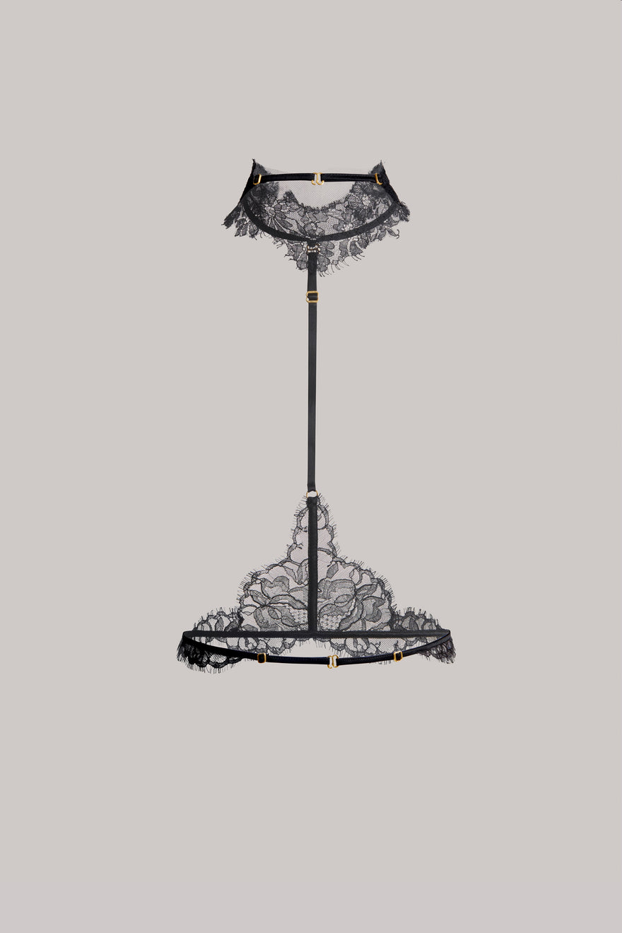 A black lace neck piece with a matching black lace harness suspended on a central black support stand, set against a solid light gray background.