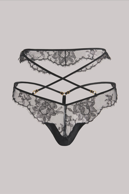 Black lace thong underwear with floral lace patterns and thin crisscross back straps, shown against a solid light gray background.