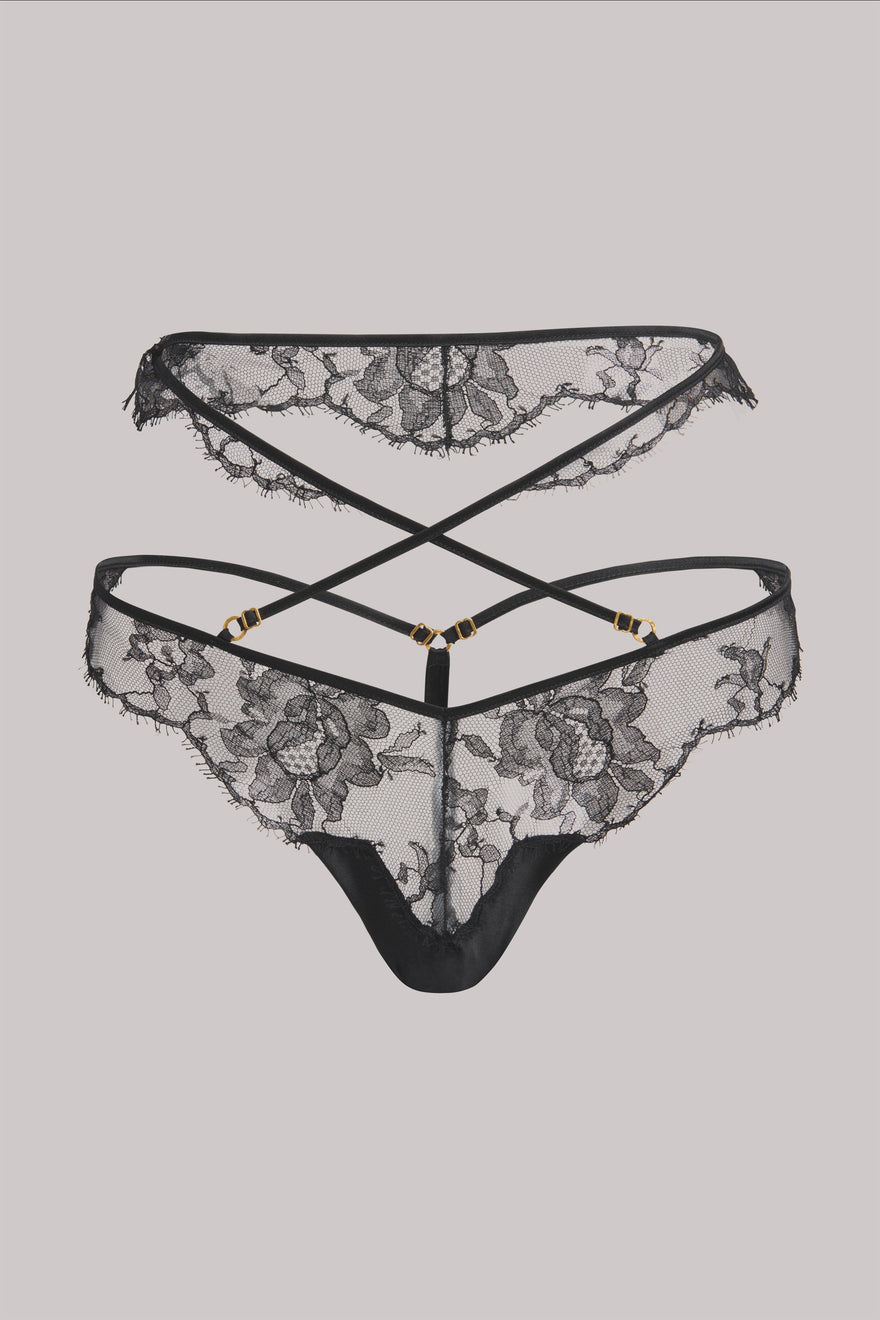 Black lace thong underwear with floral lace patterns and thin crisscross back straps, shown against a solid light gray background.