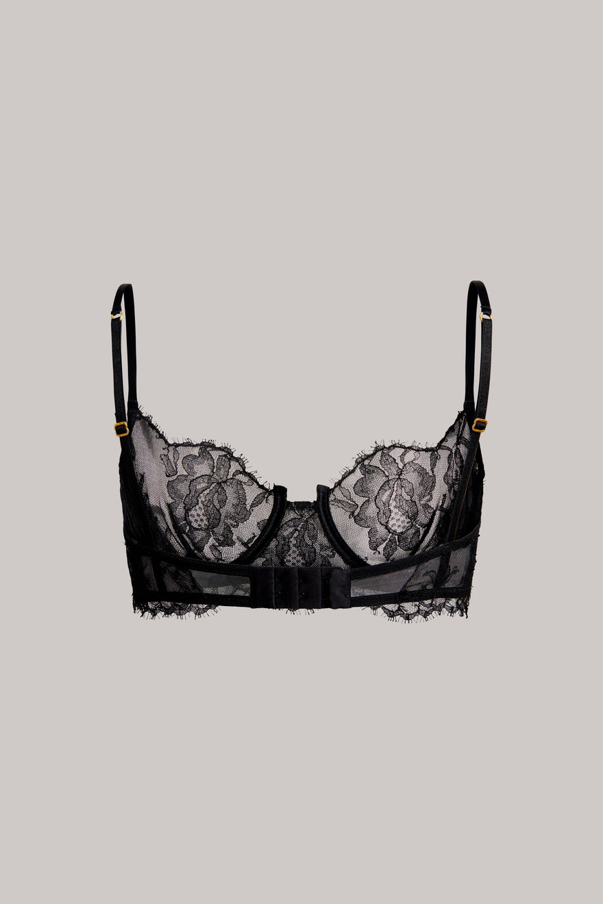 Black lace underwire bra with floral lace cups and thin adjustable shoulder straps, shown flat against a solid light gray background.