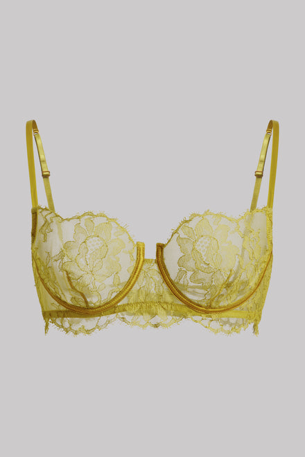 A pale yellow lace underwire bra with floral lace detailing and thin adjustable shoulder straps, shown against a solid gray background.