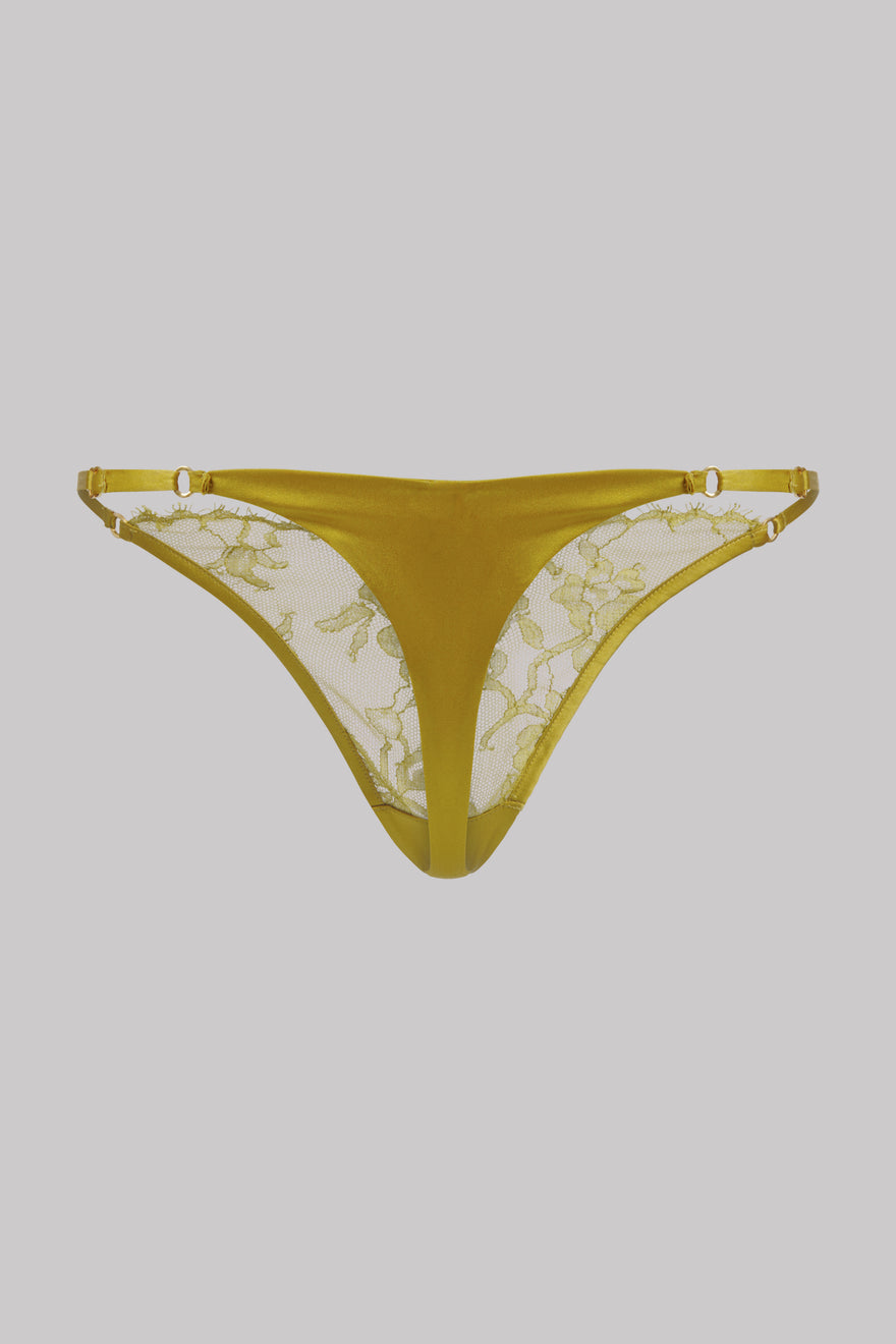A pair of women's thong-style underwear in a mustard yellow color, featuring sheer floral lace panels on the inner side and matching elastic waistband, shown against a solid gray background.