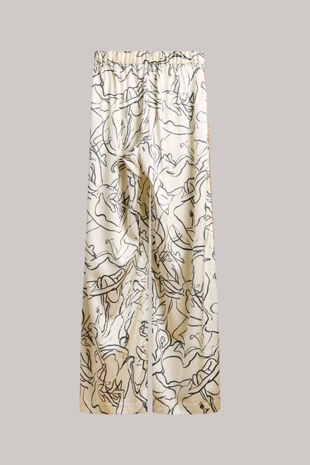 A pair of wide-leg pants featuring an abstract black line art print on a warm beige and cream base, displayed flat against a solid gray background.