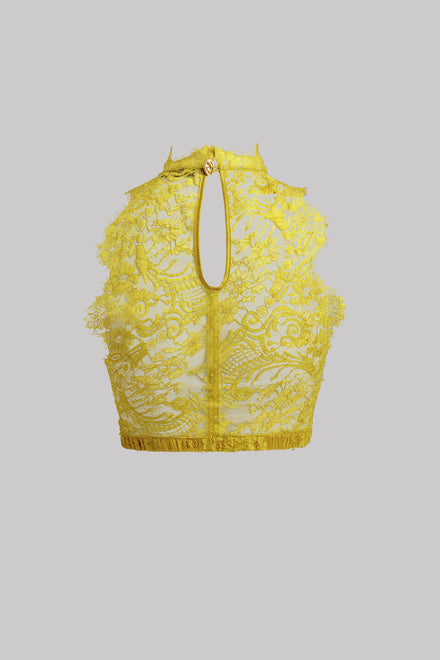 A yellow lace halter crop top with a keyhole cutout and gold-tone zipper, shown against a solid gray background.